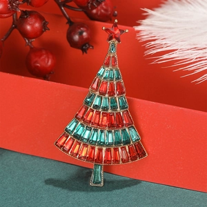 Elegant gold Christmas tree brooch with red and green crystals on a festive background