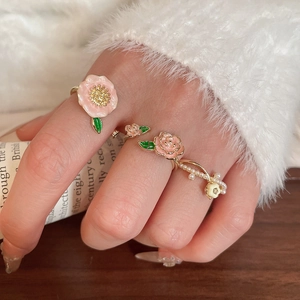 Détail d'un ensemble de bagues fleuries avec pétales roses et perles sur main