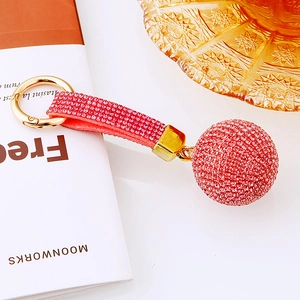 Dettaglio di un portachiavi con sfera di strass rossi, chiusura oro e cinturino rosso