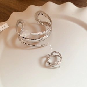 Close-up of polished silver spiral open cuff bracelet and matching ring set in a dish