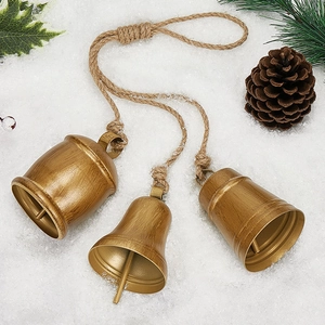 Three vintage gold metal Christmas bells with jute rope on snow background
