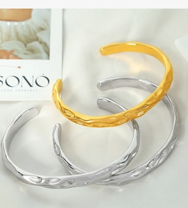Detailed view of hammered gold and silver open cuffs on elegant white silk fabric