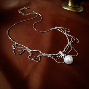 Détail du collier à franges en strass scintillants avec pendentif en perle blanche