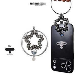 Detail of star-shaped metal phone charm with blue resin and circular clasp hook