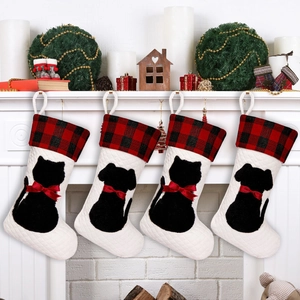 Set of four plaid Christmas stockings with dog and cat silhouettes on a white fireplace