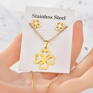 Close-up of a gold stainless steel jewelry set with hollow clover necklace and earrings