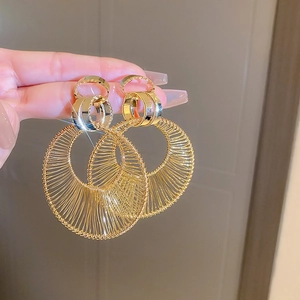 Detail of hand-held gold sunburst hoop earrings with layered interlocking rings