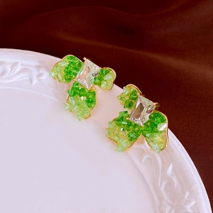 Macro view of emerald green crystal floral earrings on white ceramic with velvet back