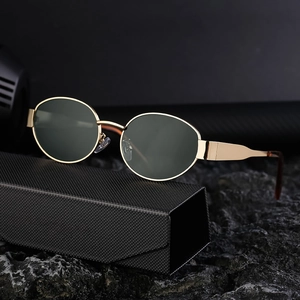 Chic oval gold metal frame sunglasses with dark green lenses on a black case