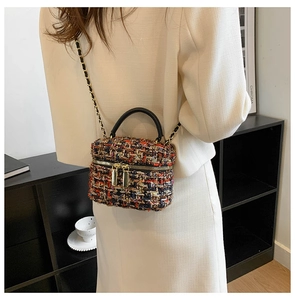 Detail van kleurrijke tweed emmer tas met gouden kettingriem en zwart handvat