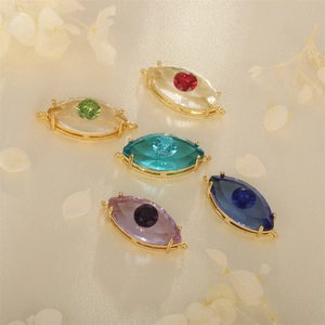Faceted evil eye pendants with gold plating and colorful crystals on beige background