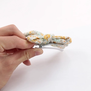 Detail view of floral cotton bow hair clip with silver metal alligator clip and white ribbon