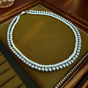 Detail of double-layer necklace with white and grey pearls on vintage brown velvet display