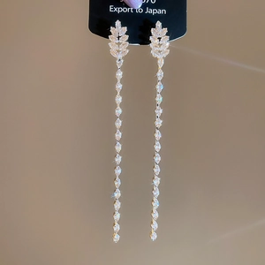 Detail of 18K gold plated long tassel earrings with sparkling zircon on a display card