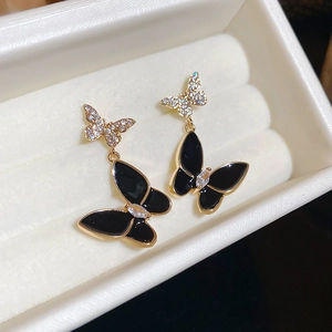 Macro view of butterfly earrings with black enamel and zircons on velvet jewelry box