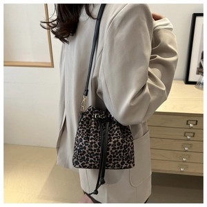 Detail of leopard print bucket bag featuring a drawstring closure and black shoulder strap