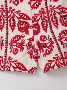 Détail de la broderie ethnique sur short en coton et lin blanc avec motifs variés