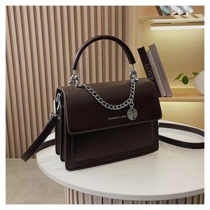 Detailed macro of dark brown textured leather crossbody bag with chic silver chain strap