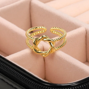 Macro shot of 18k gold plated braided open ring featuring a geometric knot on pink velvet
