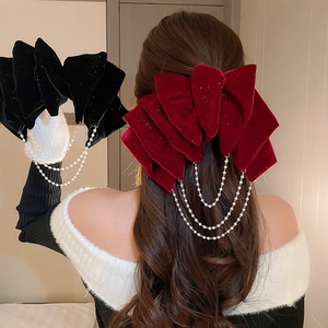 Elegant velvet bow hair clip with triple pearl chains shown on back of head