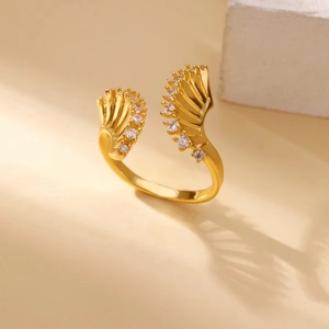 Close-up of golden open ring featuring feather design and sparkling zircon stones