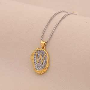 Macro shot of gold letter W pendant with sparkling pave crystals and silver bead chain