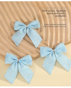 Detailed view of light blue linen-style bows with silver metal buckles on a wooden board