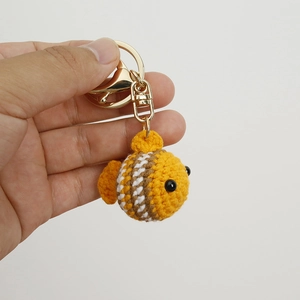 Handmade crochet clownfish keychain in yellow yarn with brown stripes and gold clasp