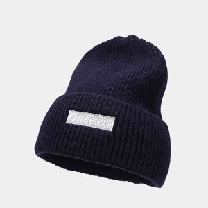Detailed texture of navy blue ribbed knit beanie featuring The Focus white embroidered label