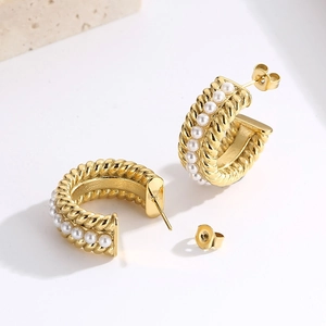 Detailed shot of gold C-shaped twisted hoop earrings with small white pearls on stone