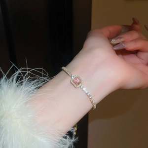 Close-up of rose gold bracelet with square pink zircon on white faux fur cuff