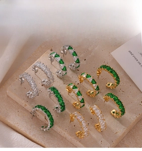 Détails macro de boucles d'oreilles en C avec zircons triangulaires plaqués or et argent