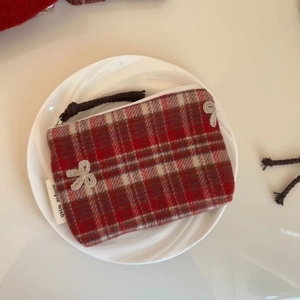 Close-up of red plaid tweed coin purse with crochet bows and simple wish woven label