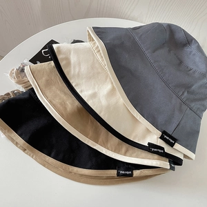 Close-up of cotton bucket hats in dark grey, beige, khaki, and black with edge piping
