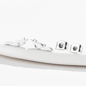 Minimalist silver running fox stud earrings set on white display stand for women