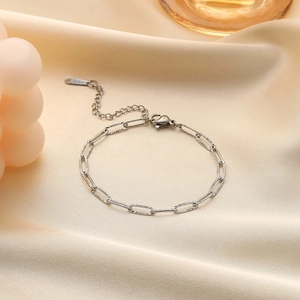 Elegant silver paperclip chain bracelet in polished steel on beige silk background