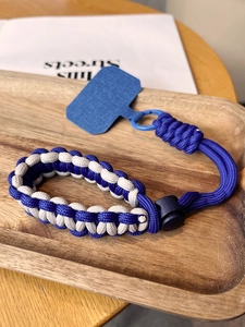 Detail of blue and white braided phone wrist strap with adjustable cord lock on wood