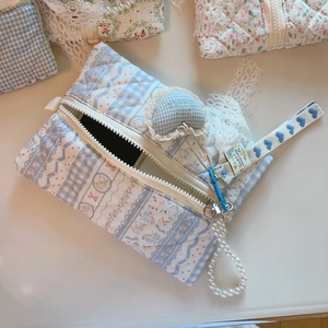Detail of blue floral quilted bag with pearl handle and sweet heart charm detail