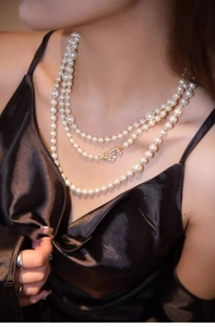 Close-up of layered pearl necklace featuring a zircon encrusted number five pendant