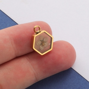 Hexagonal gold stainless steel pendant with dried flowers held between fingers