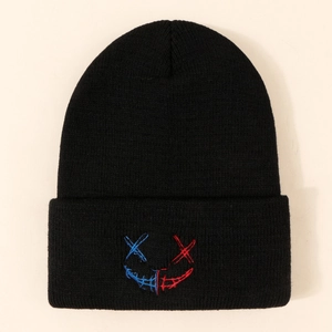 Bonnet en maille noire avec motif visage brodé bleu et rouge sur fond neutre