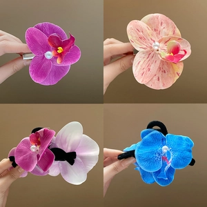 Detail of orchid hair clips in purple, pink and blue with pearl centers shown in hand