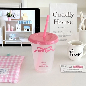 Detailed close-up of a pink matte plastic straw cup featuring a stylish bow and slogan