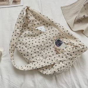 Detail of floral canvas shoulder bag showing front pocket and smartphone storage capacity