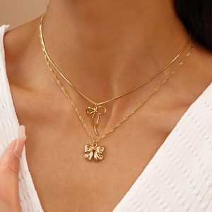Gros plan d'un collier doré à double épaisseur avec nœud porté sur un tricot blanc