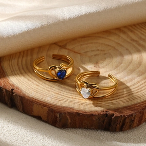 Close-up of gold flower rings with blue and white heart zircons on wood slice
