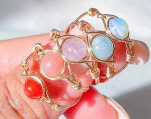 Detailed close-up of handmade gold wire wrapped rings with colorful round gemstones