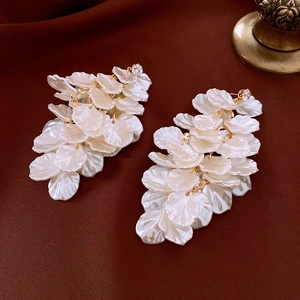 Close-up of pearl petals and gold chain tassel earrings on dark silk background