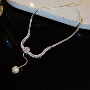 Elegante collana a catena serpente d'argento con zirconi e perla su sfondo nero