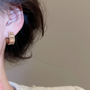 Detail of square gold hoop earring with three clear zircon stones worn by a model